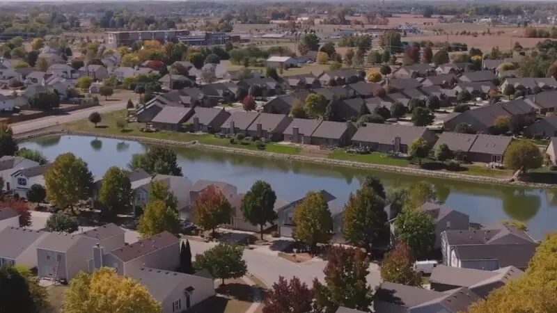 An Aerial View of A Suburban Neighborhood in Fort Wayne with Houses Surrounding a Small Pond, Showcasing the Typical Residential Landscape Compared to The State Average in Indiana