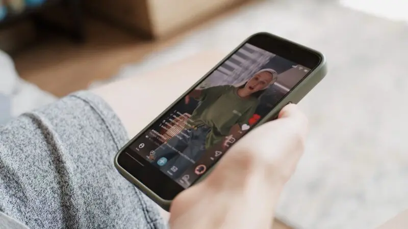  A hand holding a smartphone, displaying a TikTok video of a person speaking animatedly