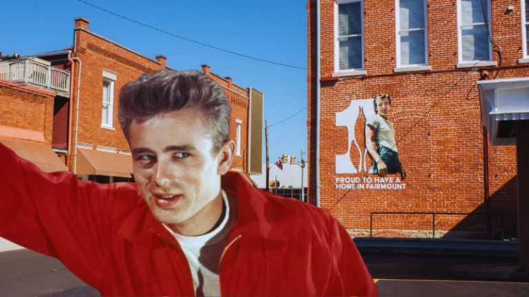 James Dean in a red jacket with a town mural in the background, featuring a tribute to him in Fairmount, Indiana.