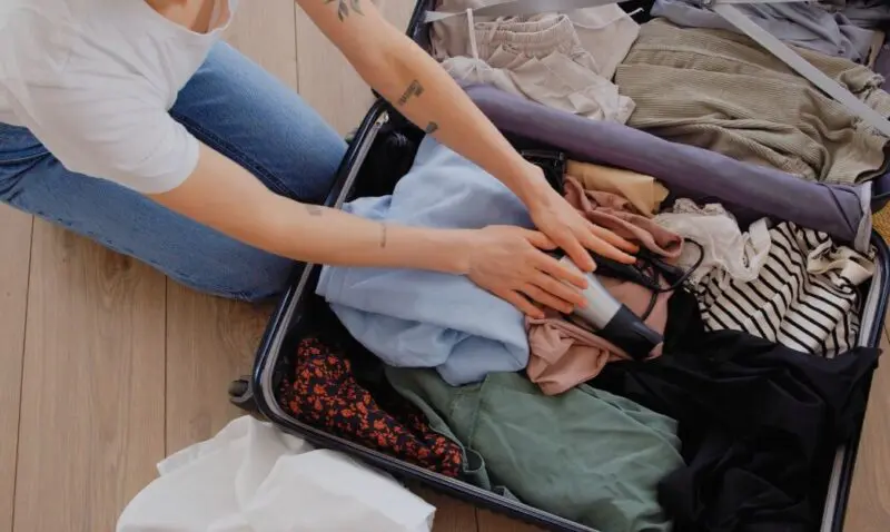 Person meticulously packing a suitcase, arranging clothes