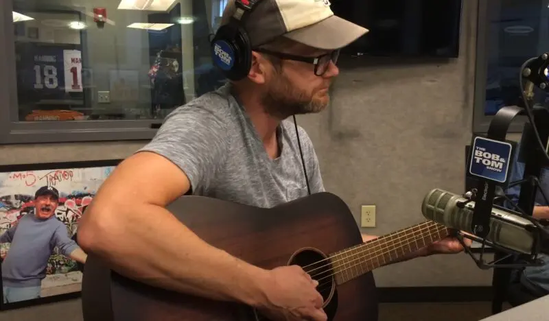 Josh Kaufman plays an acoustic guitar in a radio studio