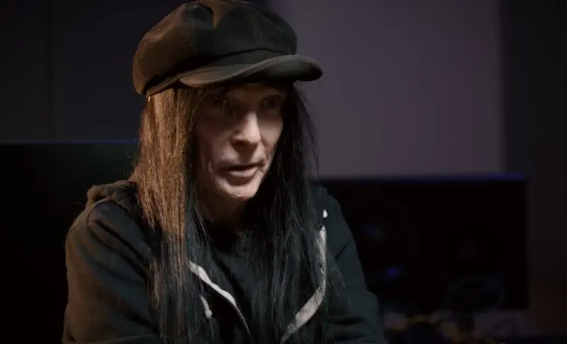 Mick Mars speaks for the camera in a music studio